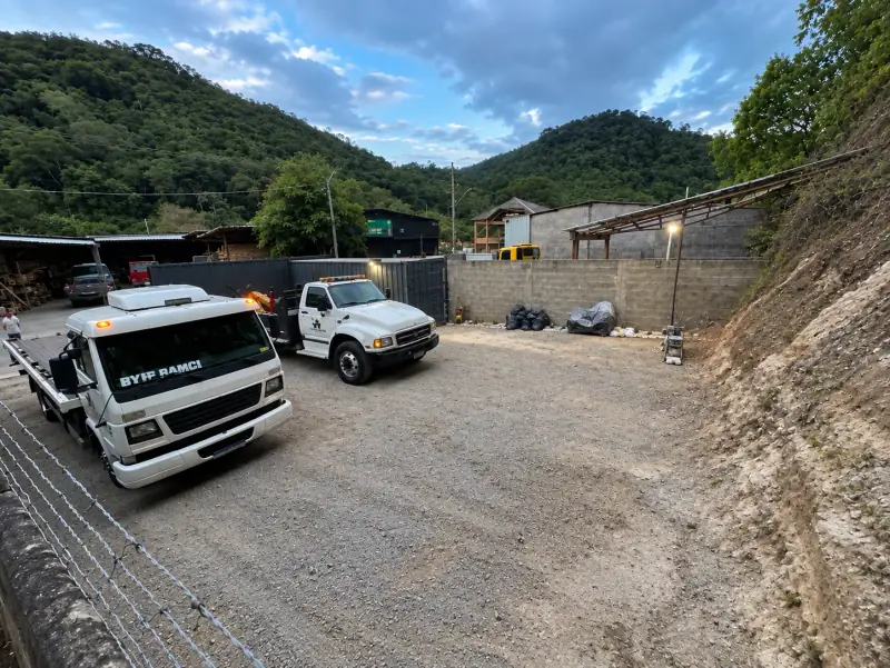 Pátio da base própria da Faller Guinchos em Domingos Martins, com dois caminhões-guincho e montanhas ao fundo.